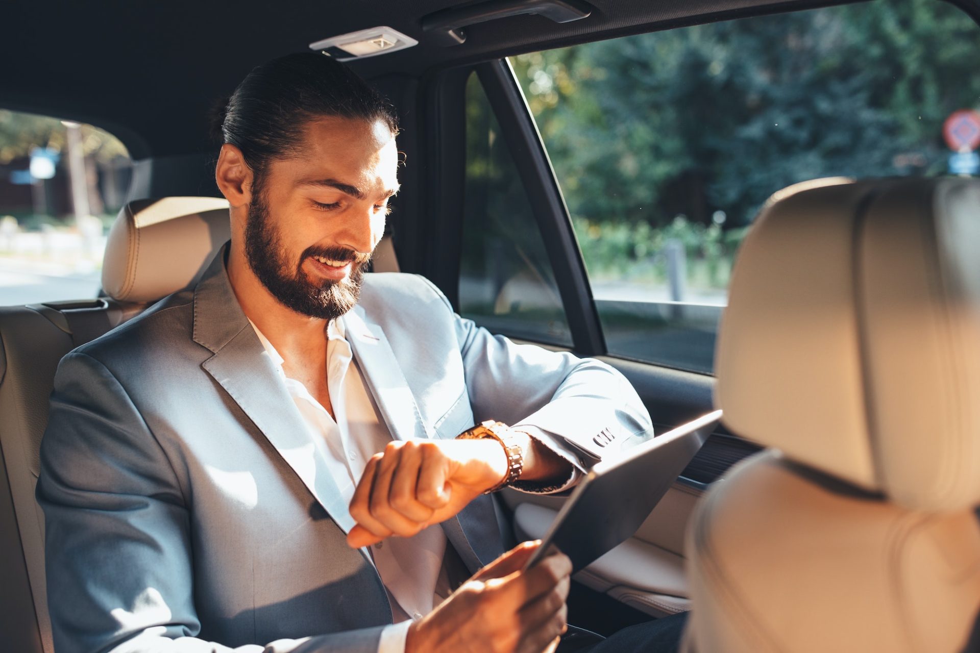 Businessman looking at the watch on the back of the limousine