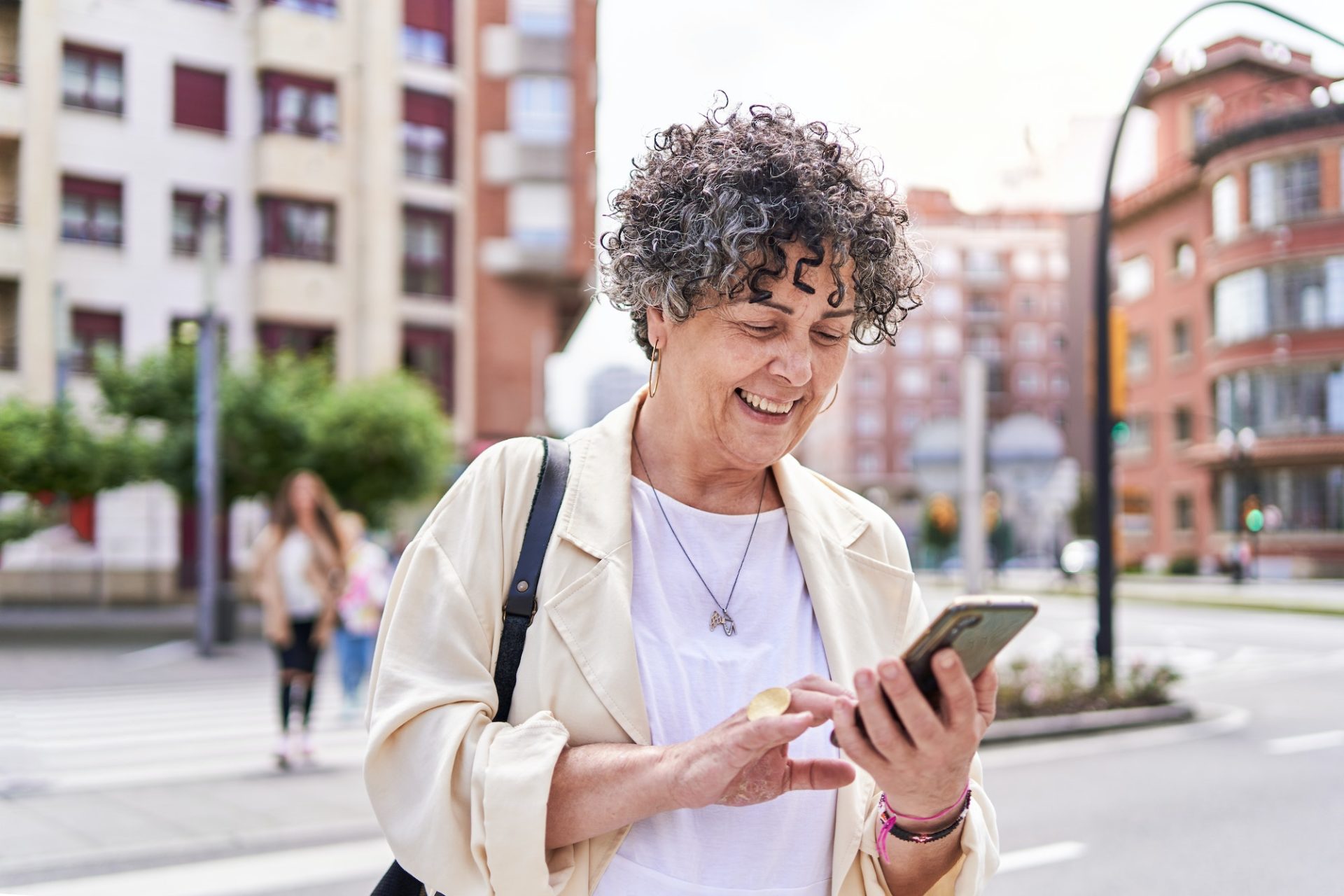 Mature woman using mobile app device on smartphone to arrange a taxi ride in downtown city street